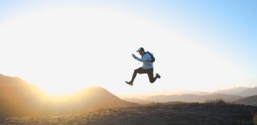 Photographie d'un homme sautant entre les montagnes